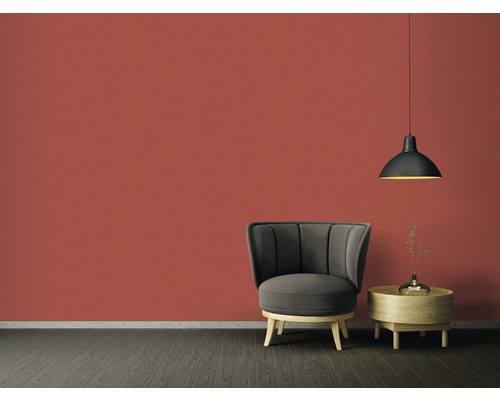 Wohnzimmer mit Sessel, Beistelltisch und Hängelampe vor einer farbigen Wand