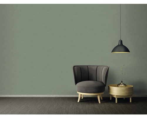 Einrichtungsbeispiel mit Sessel, Beistelltisch und Pendelleuchte vor einer grünen Wand