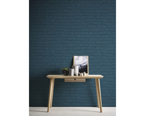 Scène avec une console en bois devant un mur en briques, décorée d''une plante, de bougeoirs et d''une photo