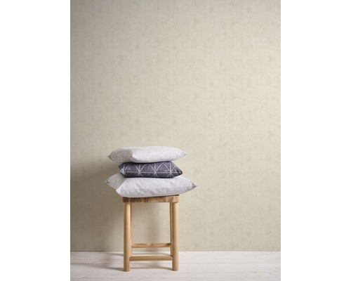 Dekorative Kissen gestapelt auf einem Hocker vor einer Wand