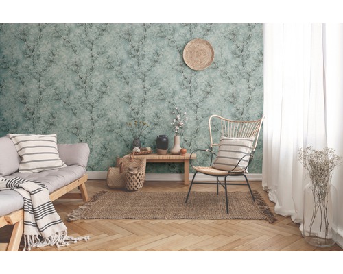 Wohnzimmer mit gemusterter Tapete, Sofa, Stuhl und Dekorationen für eine gemütliche Atmosphäre.