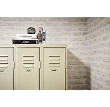 Metallspind mit Dekor und Bücherstapel vor einer Mauer in Steinoptik