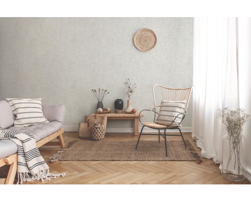 Wohnzimmer mit Sofa, Stuhl und Teppich auf Parkettboden vor einer strukturierten Wand