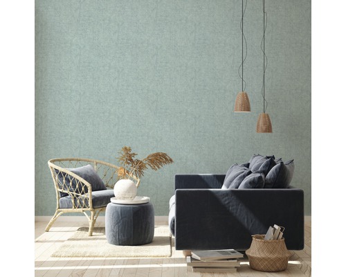 Helle, strukturierte Tapete in einem Wohnzimmer mit Sessel, Sofa und Dekorationsgegenständen.