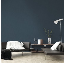 Wohnzimmer mit grauen Sofas, weißem Kissen, weißer Decke, Stehlampe und Dekorationsgegenständen auf einem Regal vor einer blauen Wand