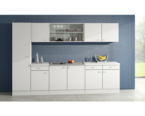 Helle Küche mit weißen Schränken und Arbeitsplatten vor einer blauen Wand.