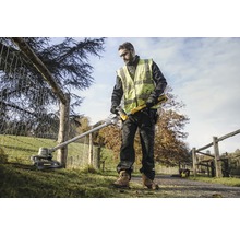 Un homme utilise un coupe-bordure DeWalt dans un jardin près d''une clôture.