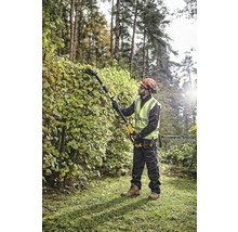 Un homme taille une haie avec un taille-haie sans fil dans le jardin.
