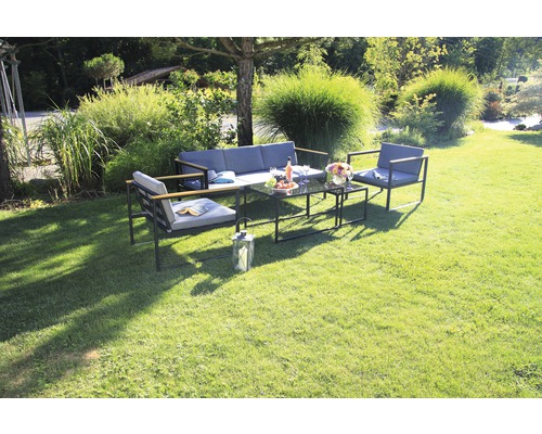 Scène de jardin avec un ensemble de meubles de salon comprenant un canapé, des fauteuils et des tables sur une pelouse