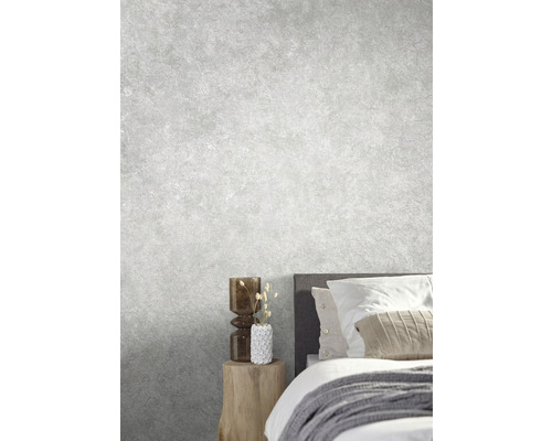 Chambre claire avec lit, table de chevet et objets décoratifs devant un mur gris