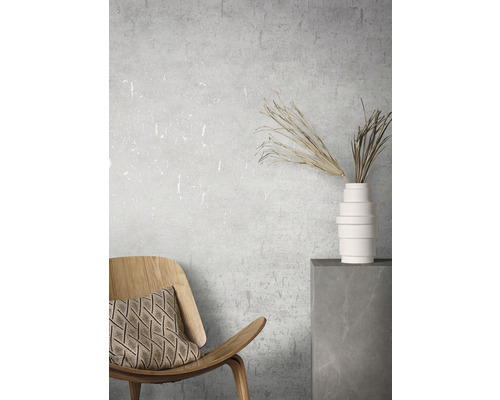 Intérieur décoratif avec chaise en bois, coussin, vase et fleurs séchées sur un socle.