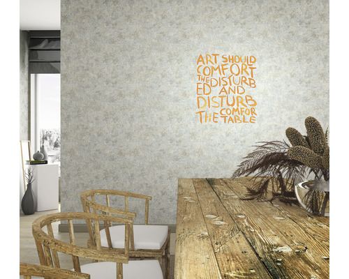 Wohnraum mit Holztisch, Stühlen und Wanddekoration mit dem Schriftzug Kunst soll die Gestörten trösten und die Gemütlichen stören.