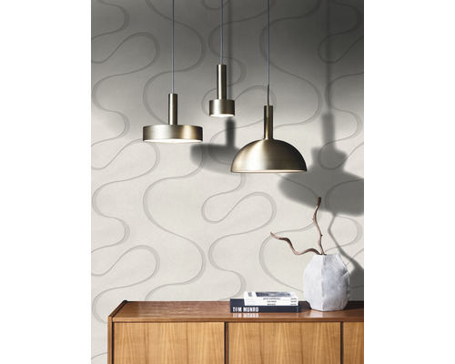 Trois suspensions en métal sont suspendues devant un mur avec un motif ondulé.