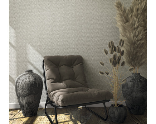 Salon avec papier peint à motifs, fauteuil et décoration dans des vases.