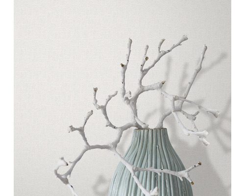 Branches décoratives dans un vase devant un papier peint