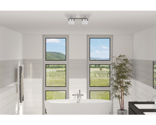 Helles Badezimmer mit freistehender Badewanne, Handtuchwärmer, zwei Fenstern mit Blick auf die Landschaft und Deckenleuchte