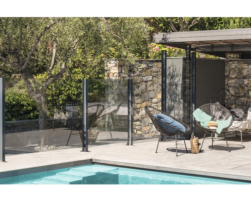 Espace piscine avec clôture en verre et coin salon dans le jardin