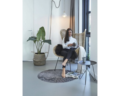 Intérieur lumineux avec fauteuil en rotin, plante, tapis et femme lisant