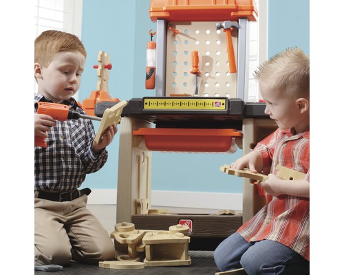 Zwei Kinder spielen mit einer Werkbank und Werkzeugen.