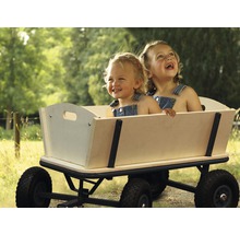 Zwei lachende Kinder sitzen in einem Bollerwagen aus Holz mit schwarzen Rädern.