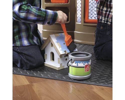Kind malt ein Spielzeughaus mit Pinsel und Farbeimer