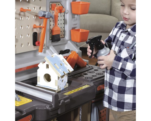 Kind spielt mit einer Werkbank und sprüht Wasser auf ein Vogelhaus