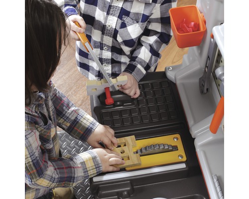 Zwei Kinder spielen mit einer Werkbank und Werkzeugen.
