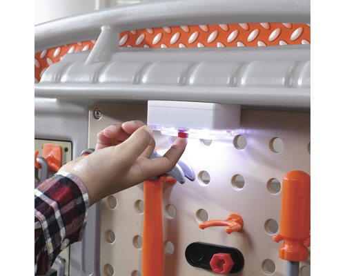 Nahaufnahme einer Werkbank mit Zubehör und einer Hand, die den Lichtschalter betätigt