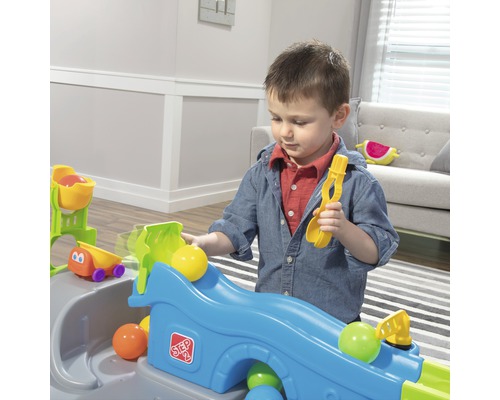 Ein Kind spielt mit einer Ballbahn von Step2 mit Bällen und einer Schaufel.