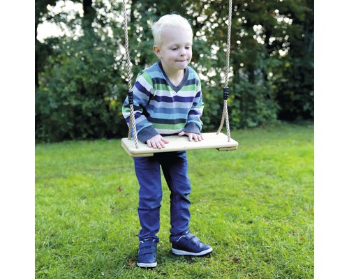 Junge auf Holzschaukel mit Seilen im Garten