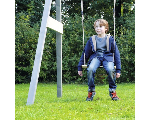 Junge schwingt auf einer Holzschaukel im Garten.