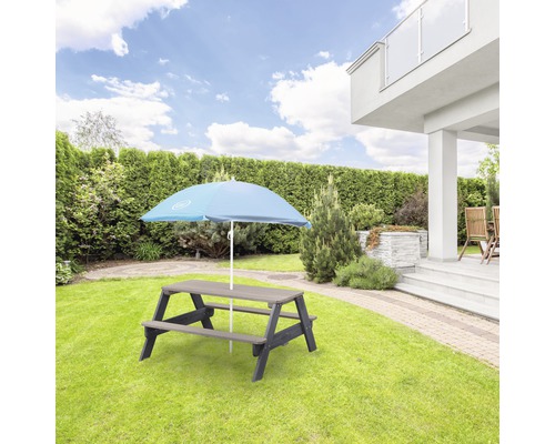 Gartenszene mit Picknicktisch und Sonnenschirm auf Rasenfläche vor Haus