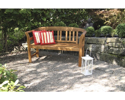 Banc de jardin en bois avec deux coussins et une lanterne dans le jardin