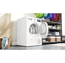 Sèche-linge à condensation autonome avec porte ouverte dans une buanderie.