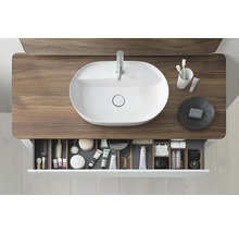 Aufnahme eines Badezimmers mit einem Waschbecken auf einem Waschtisch und einer offenen Schublade mit Badartikeln