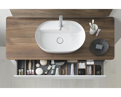 Aufnahme eines Badezimmers mit einem Waschbecken auf einem Waschtisch und einer offenen Schublade mit Badartikeln