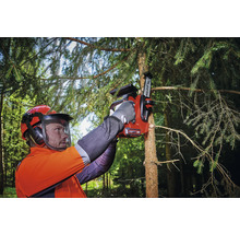 Une personne portant un équipement de sécurité utilise une tronçonneuse sans fil pour couper une branche d''arbre.