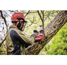 Un homme avec un casque de protection et une tronçonneuse à batterie coupe des branches d''arbre