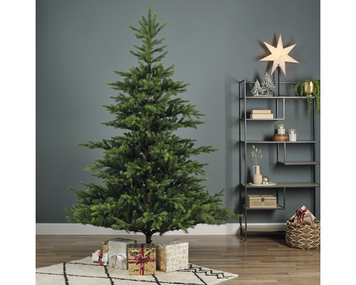 Geschmückter Weihnachtsbaum im Wohnzimmer mit Geschenken und Regal.