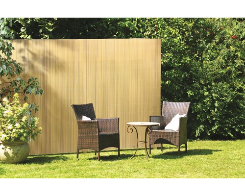 Espace jardin avec pare-vue en bambou, deux fauteuils en rotin et une petite table sur une pelouse