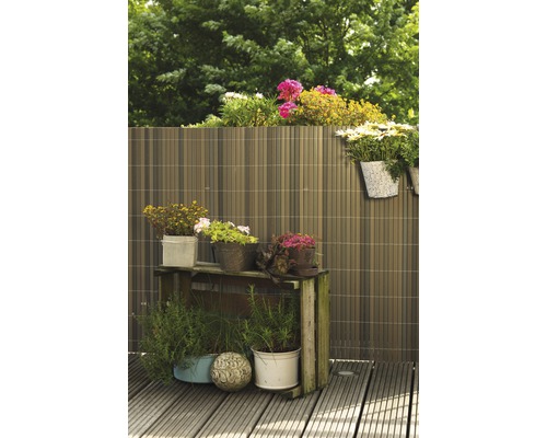 Scène de jardin avec un écran d''intimité, une table de plantation et des fleurs en pots