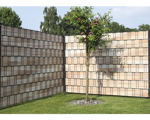 Gartenzaun mit Holzstruktur und Baum im Garten