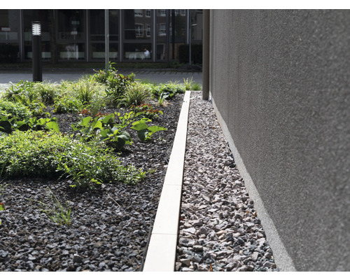 Beetbegrenzung aus Stein zwischen Pflanzen und Hauswand