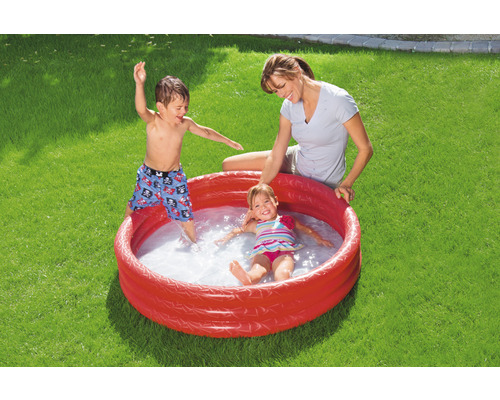 Piscine gonflable avec des enfants jouant et un adulte dans le jardin