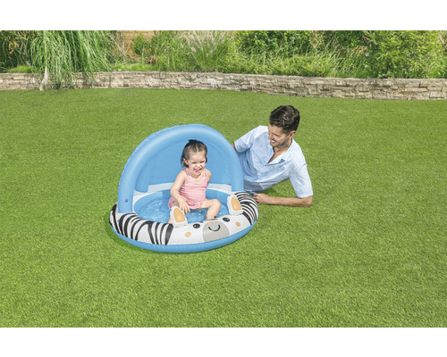 Aufblasbares Planschbecken mit Zebramuster und Sonnendach im Garten mit spielendem Kind und Erwachsenem