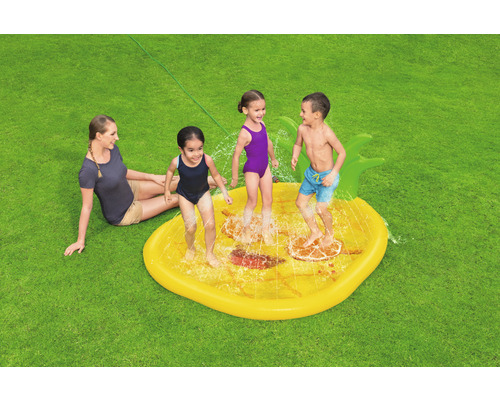 Kinder spielen auf einer gelben Wasserspielmatte in Form einer Ananas im Garten.