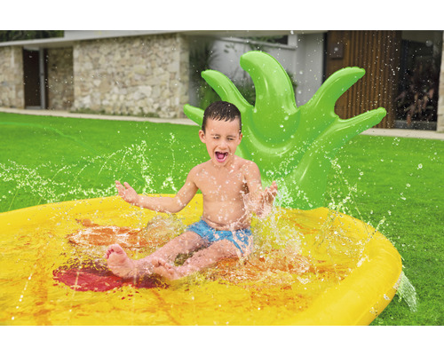 Junge rutscht auf einer aufblasbaren Wasserrutsche in Form einer Ananas