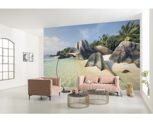 Salon avec papier peint photo d''une plage tropicale, canapé, fauteuil et tables basses