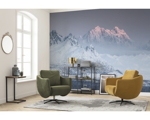 Wohnzimmer mit Fototapete mit Bergmotiv, zwei Drehsesseln und einem Beistelltisch