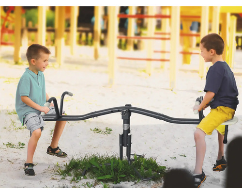 Deux enfants jouent sur une balançoire à bascule dans une aire de jeux.
